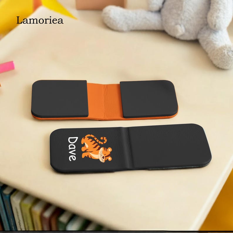 Puede incluir: Cartera negra y naranja con un dise&ntilde;o de tigre y el nombre "Dave". La cartera est&aacute; abierta, revelando un interior naranja. La marca "Lamorea" es visible en la esquina superior izquierda.