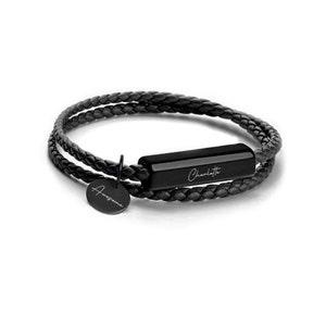 May include: Black leather bracelet with a black metal bar engraved with the name "Charlotte" and a round charm engraved with the word "Awesome".