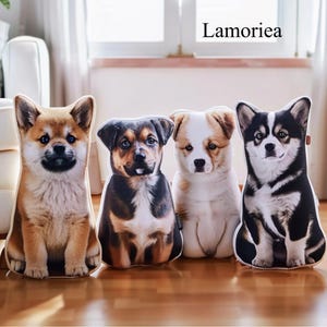 Puede incluir: Cuatro cojines decorativos con forma de perro, con im&aacute;genes impresas realistas de diferentes razas. Los cojines son de varios colores, incluyendo marr&oacute;n, negro y blanco, y est&aacute;n colocados sobre un suelo de madera. Se ve el nombre de la marca "Lamoriea".