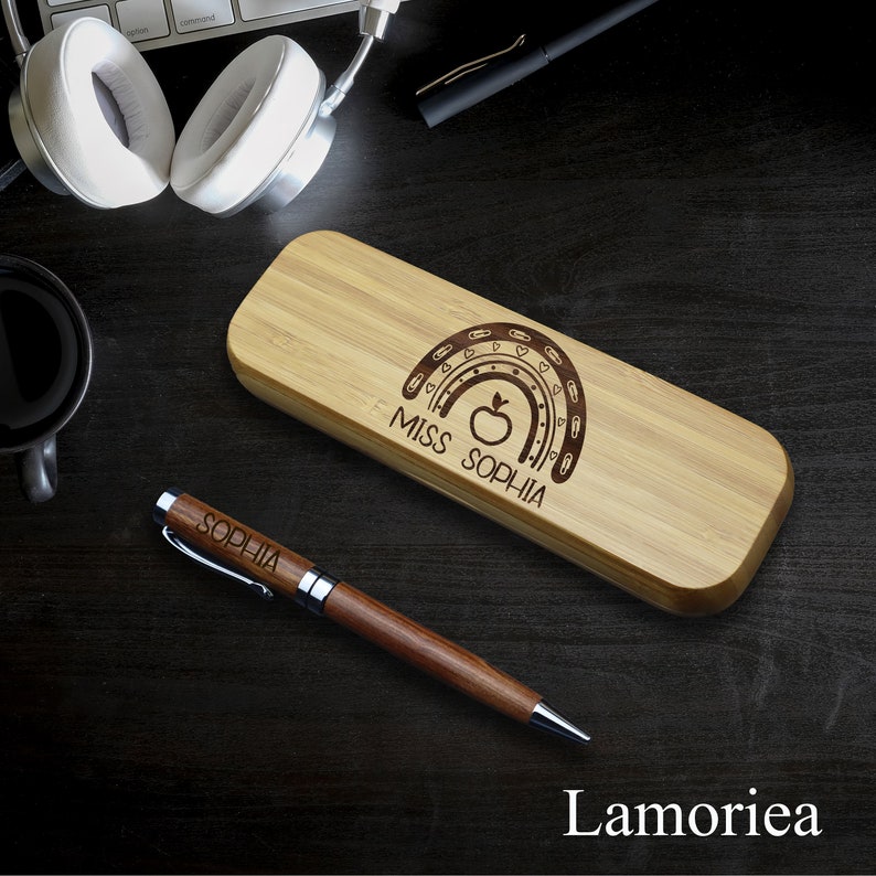 May include: A wooden pencil case with a rainbow design and the text "Miss Sophia". A wooden pen with the name "Sophia" engraved on it is next to the case.