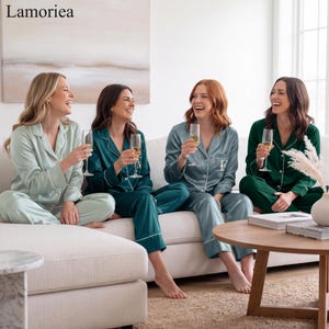 May include: Four matching long-sleeved pajama sets in varying shades of green, each featuring a button-down shirt with a collar and white piping trim, paired with matching trousers. The fabric has a smooth, satin-like finish and sheen.