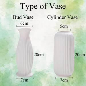 May include: Two white ceramic vases, one bud vase and one cylinder vase. The bud vase is 6 inches tall and 7 inches wide. The cylinder vase is 5 inches tall and 7 inches wide. Both vases have a ribbed design.