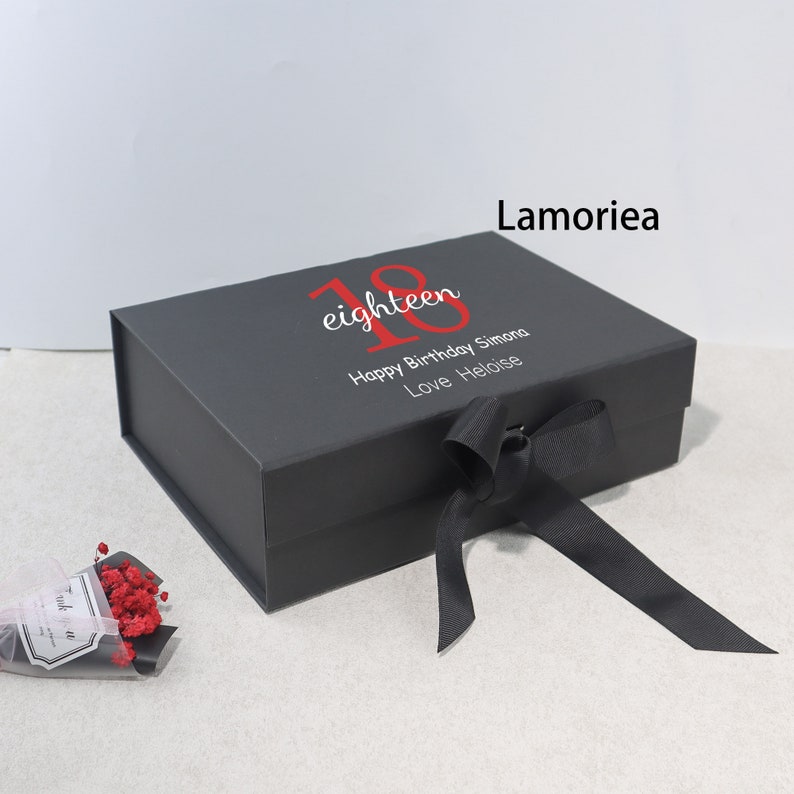 May include: Black gift box with a black ribbon and the text "eighteen" in red. The box also has the text "Happy Birthday Simona Love Heloise".