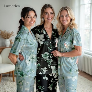 Peut inclure: Trois femmes portant des ensembles de pyjamas à imprimé floral assortis. L'un est noir avec des fleurs blanches et vertes, les deux autres sont bleu clair avec des fleurs blanches et vertes. Chaque haut de pyjama a une initiale personnalisée.