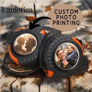 Peut inclure: Deux mètres ruban noirs et orange avec des faces rondes en métal. Chaque face a une photo d'un père et d'un enfant. Le texte "CUSTOM PHOTO PRINTING" est sur une étiquette brune.