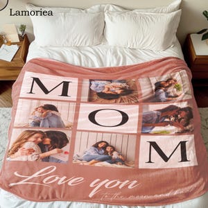 May include: A pink fleece blanket with a photo collage of a mother and her children. The blanket has the word "MOM" spelled out in black letters and the phrase "Love you to the moon and back" in white cursive writing.