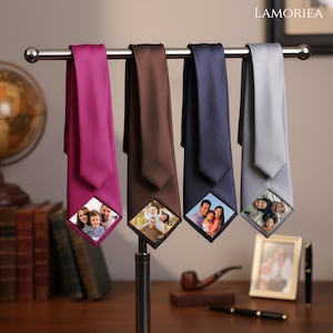 May include: Four neckties in magenta, brown, navy blue, and light gray hanging on a metal display rack. Each tie features a diamond-shaped custom photo print at the bottom tip, displaying different family portraits. The brand name LAMORIEA is visible.