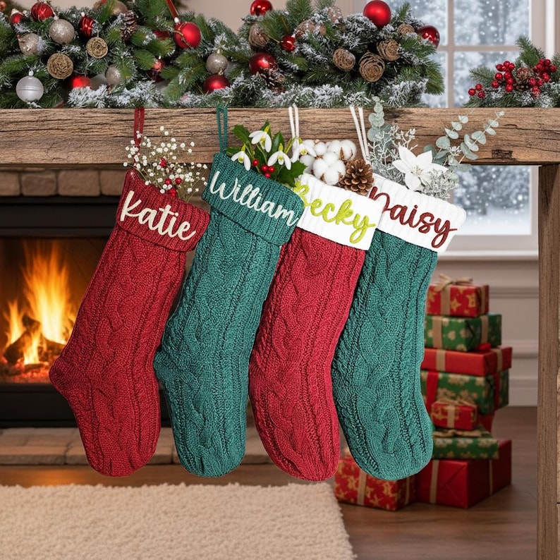 May include: Four cable-knit Christmas stockings in red and green hang from a wooden mantel. Each stocking is personalized with a name: Katie, William, Becky, and Daisy. The stockings are decorated with greenery and are near a fireplace.