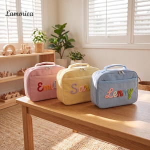 Puede incluir: Tres bolsas de almuerzo rectangulares de pana en rosa pastel, amarillo y azul claro. Cada bolsa cuenta con un asa superior, un bolsillo frontal con cremallera y un nombre personalizado en letras de tela coloridas, en relieve y cursivas.