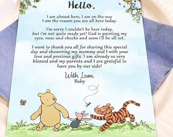 May include: A Winnie the Pooh themed baby shower card with a blue, green, and yellow background. The card features Winnie the Pooh, Piglet, and Tigger walking through a field of grass. The text on the card reads "Hello, I am almost here, I am on the way. I am the reason you are all here today. I'm sorry I couldn't be here today, but I'm not quite ready yet! God is painting my eyes, nose and cheeks and soon I'll be all set. I want to thank you all for sharing this special day and showering my mommy and I with your love and precious gifts. I am already so very blessed and my parents and I are grateful to have you by our side! With Love, Baby."
