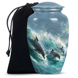 May include: A blue and silver metal urn with a depiction of three dolphins jumping out of the water. The urn has a lid and comes with a black velvet drawstring bag.