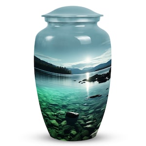 May include: A light blue ceramic urn with a scenic image of a lake with mountains in the background. The lake is clear and you can see rocks at the bottom. The sun is shining on the water.