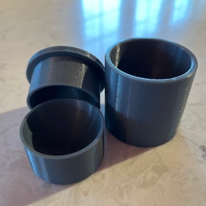 Peut inclure: Trois contenants en plastique gris de différentes tailles, empilés les uns sur les autres.