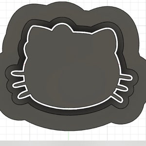 Peut inclure: Un emporte-pièce gris en forme de visage de chat. L'emporte-pièce a une double couche, avec une couche extérieure légèrement plus grande et une couche intérieure plus petite.