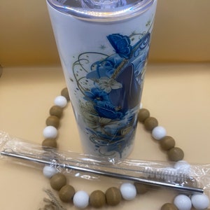 Puede incluir: Un vaso de acero inoxidable blanco con un dise&ntilde;o floral azul y dorado con mariposas. El vaso tiene una tapa transparente y viene con una pajita de acero inoxidable y un cepillo de limpieza.