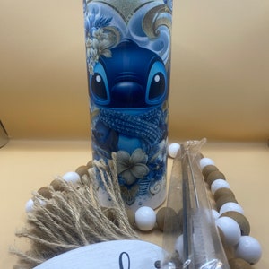 Puede incluir: Un vaso de acero inoxidable azul y blanco con un dise&ntilde;o de personaje de dibujos animados. El personaje es azul con ojos grandes y una bufanda azul. El vaso tiene una tapa blanca y una pajita.