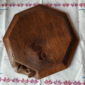 May include: A handcrafted, octagonal wooden tray with a rich, dark brown finish. The tray features a natural wood grain pattern and a unique knot detail. The edges are slightly raised, and the tray appears to be carved from a single piece of wood.