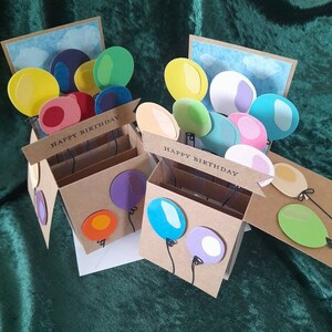 Gelukkige verjaardag 3D pop-up boxkaart met ballonnen in regenboog van kleuren. Handgemaakte wenskaart kan worden gepersonaliseerd of aangepast