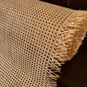 K&ouml;nnte beinhalten: Eine Rolle aus nat&uuml;rlichem Rohrgeflecht mit Fransenkante. Das Geflecht ist in einem Rautenmuster gewebt und wird h&auml;ufig f&uuml;r Stuhlsitze und -lehnen verwendet.