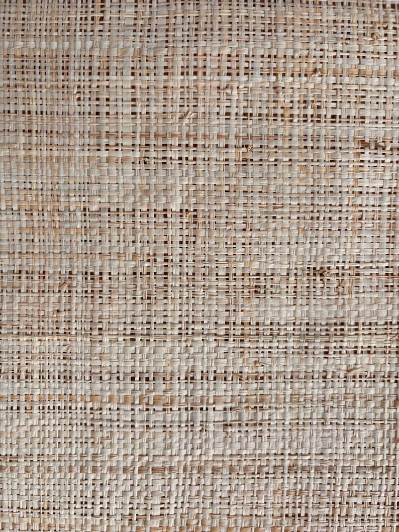 May include: Close-up of a woven natural fiber material. The texture is a tight weave of light brown and beige strands, creating a grid-like pattern. The material appears to be a natural fiber, possibly used for home decor or crafts.