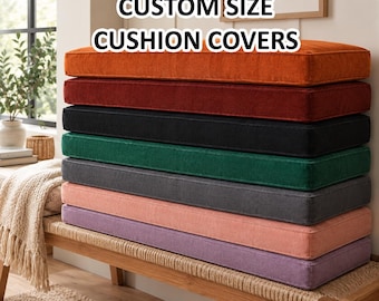 May include: A stack of rectangular cushion covers in various solid colours including orange, red, black, green, dark grey, light pink, and purple. The text CUSTOM SIZE CUSHION COVERS is displayed in white letters with a black outline above the stack.