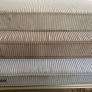 May include: Three corduroy fabric samples in beige, flesh, and sand gray colors. The fabric has a vertical ribbed texture.