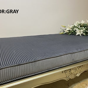 May include: Gray corduroy bench cushion with a gold ornate base. The cushion is striped and has a thick, padded design.  COLOR: GRAY