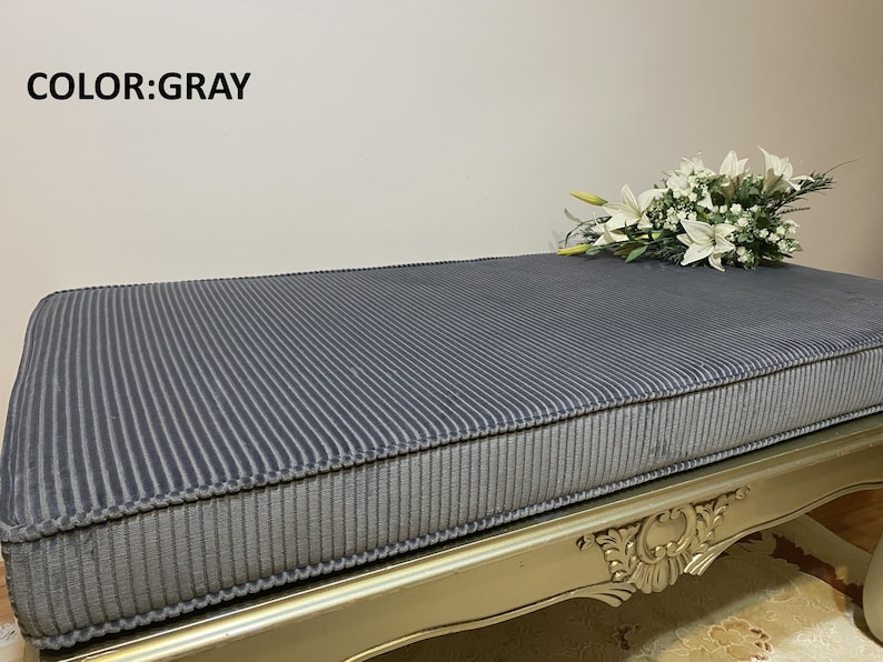 May include: Gray corduroy bench cushion with a gold ornate base. The cushion is striped and has a thick, padded design.  COLOR: GRAY