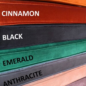 May include: A stack of seven fabric swatches in various colours, including lilac, salmon, anthracite, emerald, black, cinnamon, and tobacco. Each swatch has the colour name printed on it.