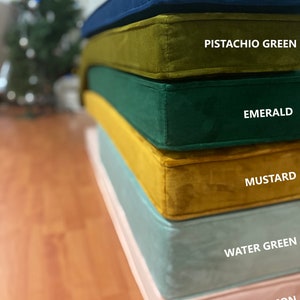 May include: Stack of six velvet cushions in different colours: navy blue, pistachio green, emerald green, mustard yellow, water green, and salmon pink.