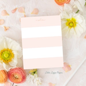 May include: A pink and white striped note card with the word "notes" written in cursive at the top. The card is surrounded by white and pink flowers and petals. The text "Little Lizzie Paper" is printed at the bottom of the card.