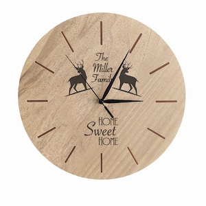 Puede incluir: Un reloj redondo de madera con una esfera negra y agujas negras. El reloj tiene un acabado de madera marrón con veta de madera y presenta una silueta de ciervo, el texto "The Miller Family" y la frase "Home Sweet Home".
