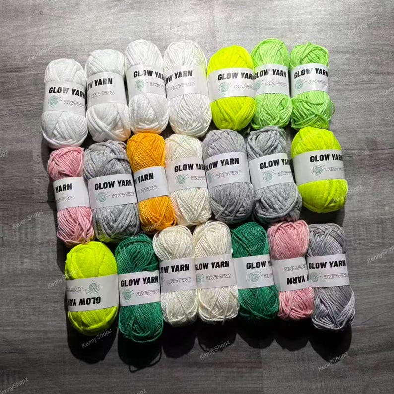 May include: A collection of twenty-four skeins of yarn arranged in a grid. The yarn comes in various colors including white, neon yellow, light green, grey, pink, orange, and dark green. Each skein features a white paper label printed with Glow Yarn.