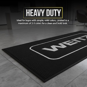 a black and white floor mat with a logo on it, placed on a tiled floor.