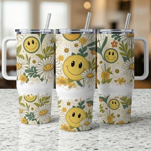 May include: Three stainless steel tumblers with a white background and a floral pattern featuring yellow daisies and smiling faces. The tumblers have a lid and a straw.