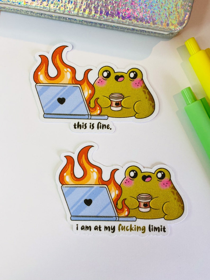 Op de afbeelding: Twee gestanste stickers met een groene kikker met roze wangen die een koffiebeker vasthoudt naast een laptop die omringd is door oranje en gele vlammen. De bovenste sticker bevat de tekst this is fine. De onderste sticker bevat de tekst i am at my fucking limit.