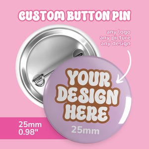Puede incluir: Un pin de botón personalizado con una cara lila claro y una parte trasera plateada. El pin presenta el texto "YOUR DESIGN HERE" en letras marrones. El pin tiene 2,5 cm de diámetro. El texto "CUSTOM BUTTON PIN" está en la parte superior.
