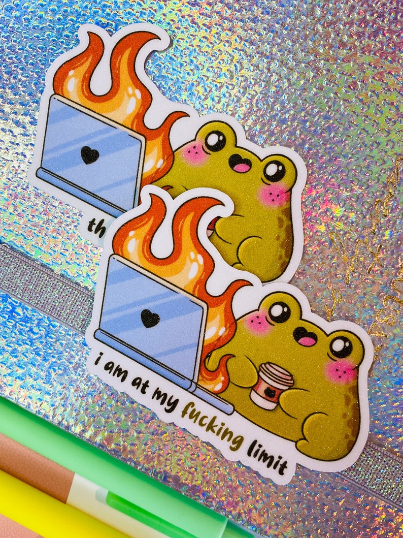 Op de afbeelding: Twee gestanste stickers met een groene kikker met roze wangen die een koffiebeker vasthoudt naast een laptop die in oranje vlammen opgaat. De tekst "i am at my fucking limit" staat in zwarte kleine letters onder de laptop en de kikker.