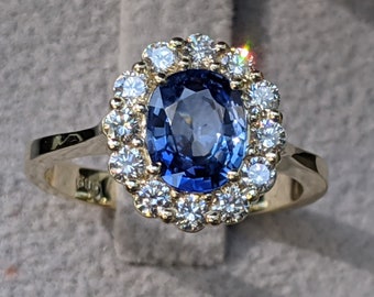 May include: A gold ring with a large oval blue sapphire surrounded by a halo of smaller diamonds.
