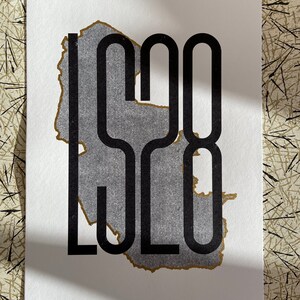 May include: A black and gold print of the number "1928" with a distressed, torn paper effect.