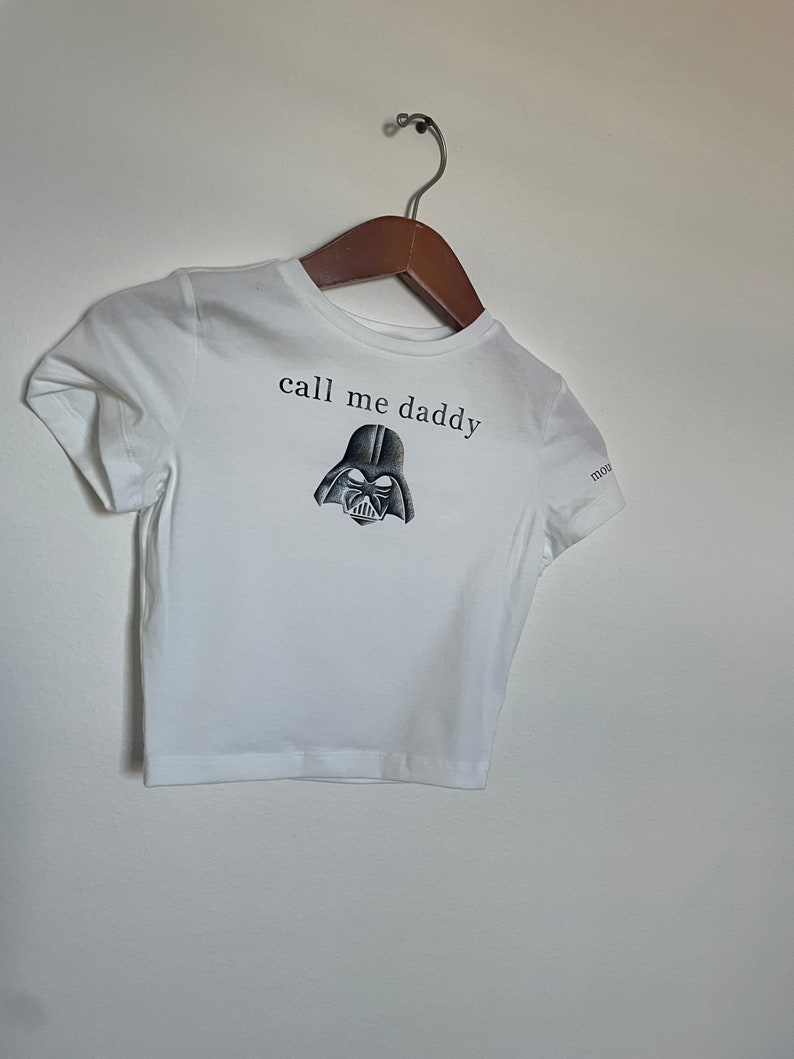 Op de afbeelding: Wit kort T-shirt met een zwart-witte illustratie van Darth Vaders hoofd en de tekst "call me daddy".