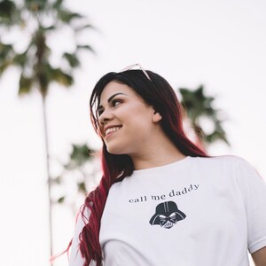 Op de afbeelding: Een wit T-shirt met een zwarte Darth Vader-afbeelding en de tekst "call me daddy" gedrukt op de voorkant.