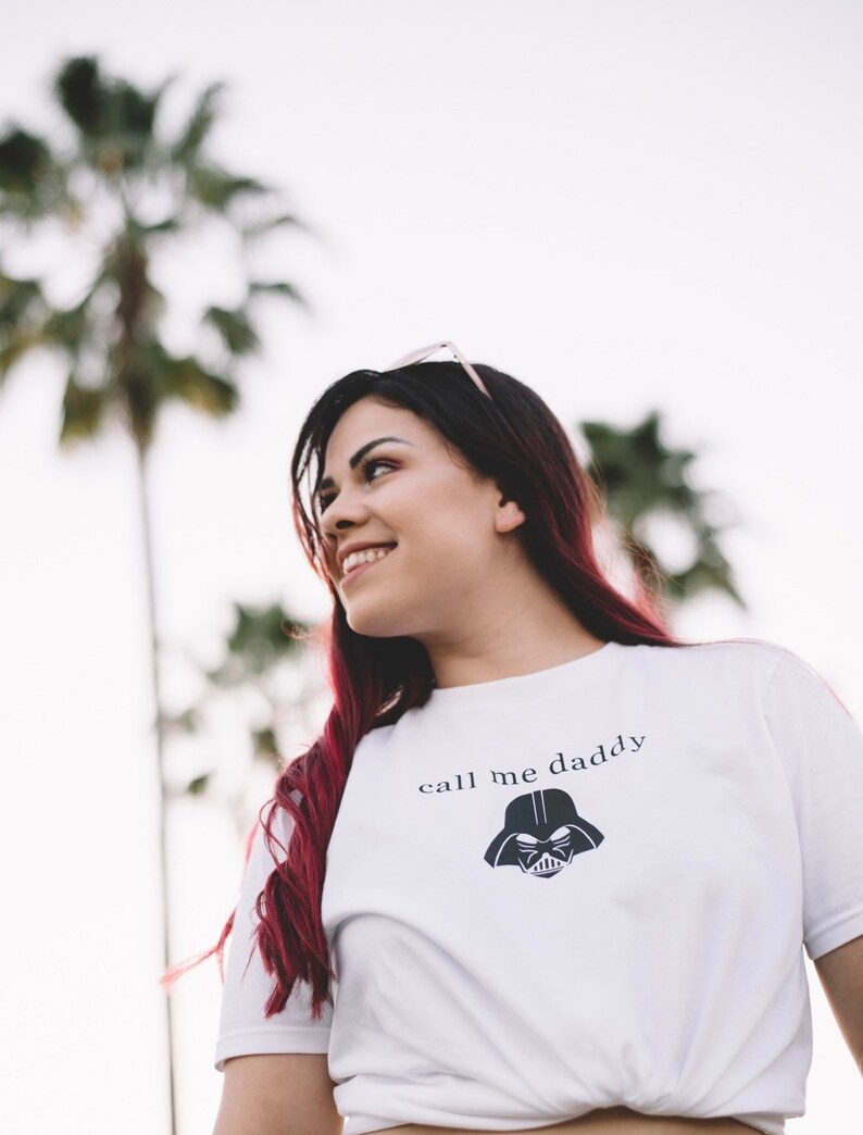 Op de afbeelding: Een wit T-shirt met een zwarte Darth Vader-afbeelding en de tekst "call me daddy" gedrukt op de voorkant.