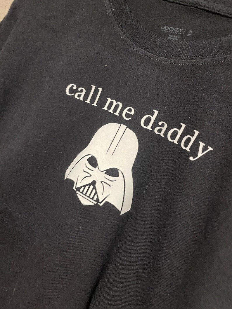 Op de afbeelding: Zwart T-shirt met een witte afbeelding van Darth Vaders hoofd en de tekst "call me daddy".