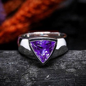 May include: A silver ring featuring a triangular purple amethyst gemstone.