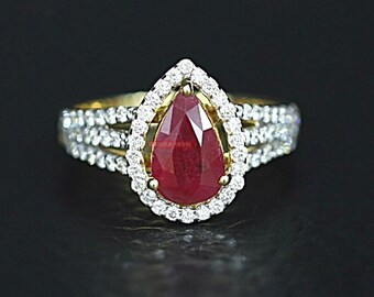 May include: A pear-shaped ruby ring set in a gold band with a halo of diamonds. The ring has a triple band design with diamonds set in each band.
