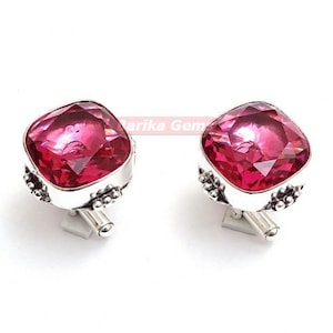 May include: A pair of silver cufflinks with a square, pink gemstone in the centre of each cufflink.