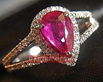 May include: A pear-shaped ruby ring with a diamond halo setting. The ring has a split shank with diamond accents.