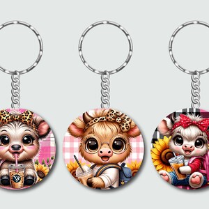 May include: Three keychains with round, colorful, cartoon cow designs. Each cow is wearing a different outfit and holding a different accessory. The keychains are attached to silver key rings.