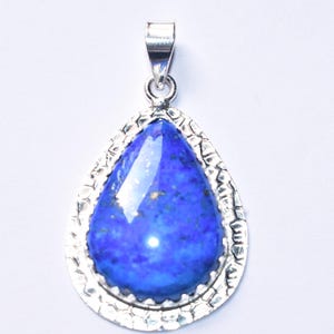 以下が含まれることがあります： 銀色のテクスチャードフレームにセットされた、鮮やかな青色の宝石が付いた、涙の形をしたペンダント。ペンダントにはチェーン用のベイルが付いています。宝石は研磨された反射面を持っています。